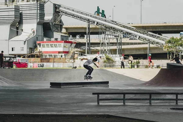 Männliches Skaten im Skatepark mit Gebäude und Menschen im Hintergrund — Stockfoto