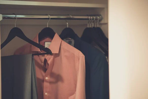 Closeup tiro de roupas masculinas penduradas em cabides em um guarda-roupa — Fotografia de Stock