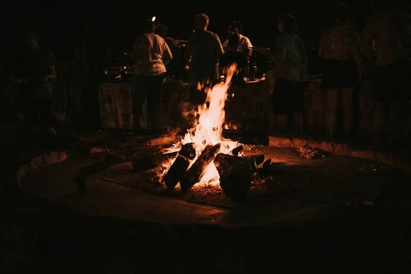 Dřevo hoří v pozdní noci táborák lidé v pozadí — Stock fotografie