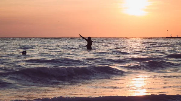 Ampia ripresa di una persona in piedi in un mare durante l'ora d'oro — Foto Stock