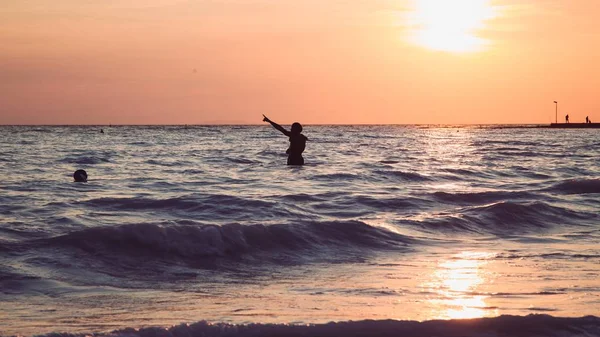 Largo disparo de una persona que se encuentra en un mar durante la hora de oro — Foto de Stock