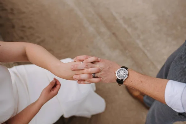 Closeup shot of a male and female holding hands on a brown background — Stock Photo, Image