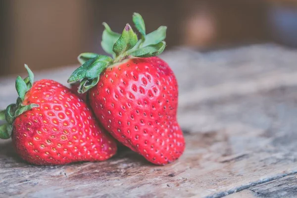 Nahaufnahme frischer reifer Erdbeeren auf einem unscharfen hölzernen Hintergrund — Stockfoto