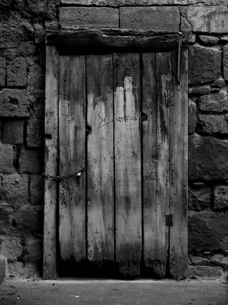 Tiro preto e branco de uma velha porta de madeira de uma casa de pedra — Fotografia de Stock