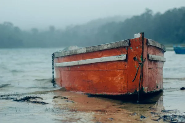 Rybářská loď štěkala na pláži v deštivý den u jezera — Stock fotografie