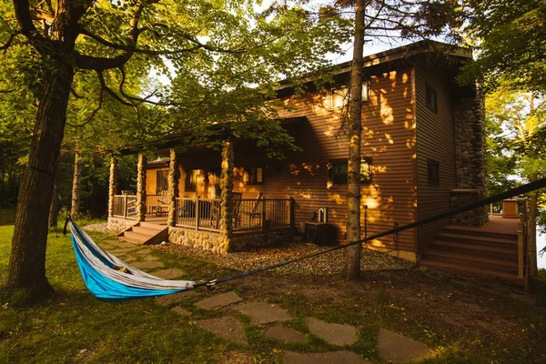 Beau cliché d'une cabane en bois et d'un hamac bleu pendu aux arbres dans la cour — Photo