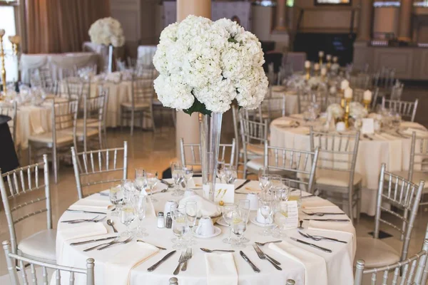 Shot of a white flower bouquet in a long glass vase on a wedding table — Stock Photo, Image