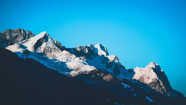 Hermosa toma de montañas nevadas rocosas con increíble cielo claro en el fondo — Foto de Stock