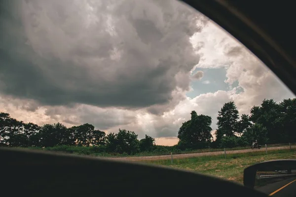 Beau cliché de ciel nuageux au-dessus des arbres pris d'une voiture — Photo