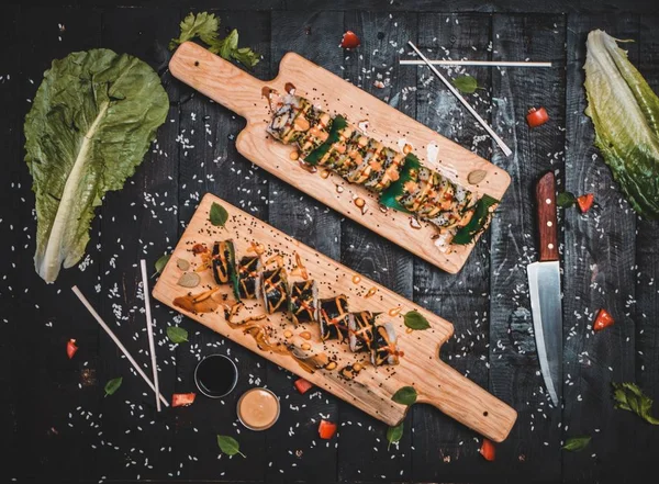 Två trä tallrikar med sushi placerad på ett bord med kniv och sallad — Stockfoto