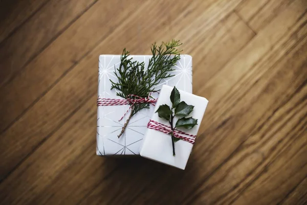 Zbliżenie białe pudełka na prezenty owinięte czerwonymi nitkami i listwami na drewnianej powierzchni — Zdjęcie stockowe