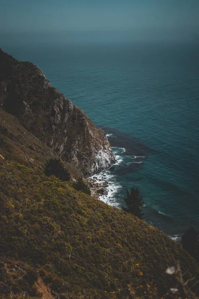 丘陵绿色海岸和蓝色海洋与岩石的垂直拍摄 — 图库照片