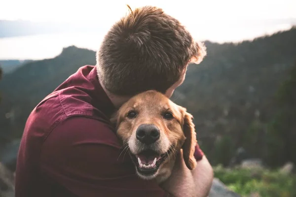 Ein Männchen Umarmt Einen Niedlichen Hund Mit Verschwommenem Natürlichen Hintergrund — Stockfoto