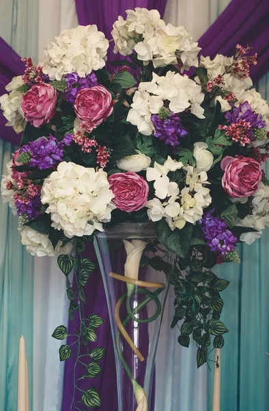 Красивый вертикальный снимок букета цветов в длинной стеклянной вазе — стоковое фото