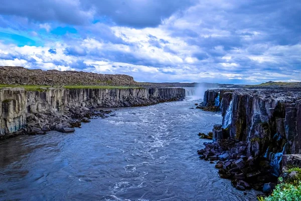 Hermoso chorro de agua en medio de dos acantilados rocosos con una cascada en la distancia — Foto de Stock