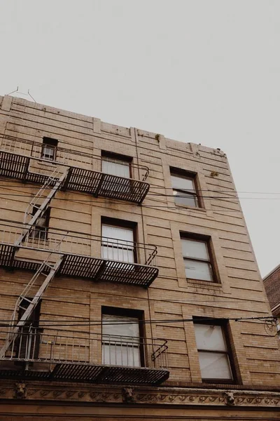 Baixo ângulo tiro de edifícios de apartamentos com escada de emergência no lado perto de janelas — Fotografia de Stock