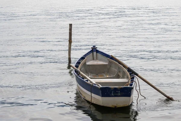Roeiboot aangemeerd op het water naast een houten plank — Stockfoto