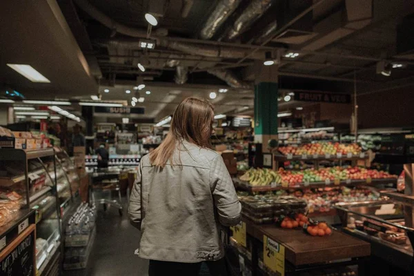 Femmina a piedi e guardando in giro in un negozio di alimentari — Foto Stock