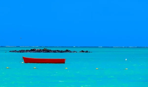 Beautiful shot of a red wooden boat resting on the water under a clear blue sky — Stock Photo, Image