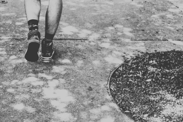 Närbild till manliga fötter gå på cement med smuts på sidan skott i svart och vitt — Stockfoto