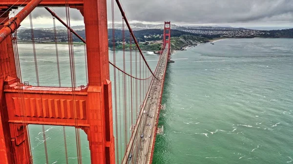 Güzel büyük bir nehrin üzerindeki uzun kırmızı asma köprünün havadan görüntüsü. — Stok fotoğraf
