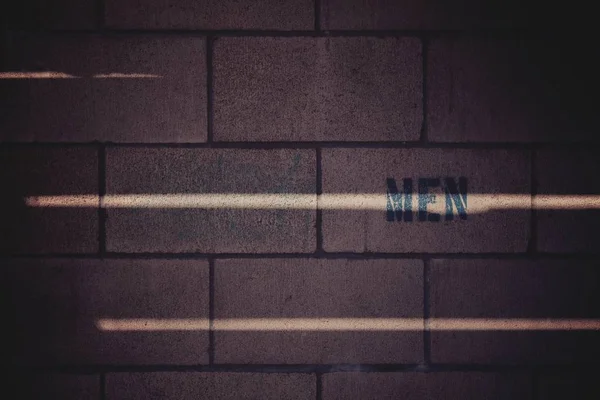 Tiro de close-up de uma parede marrom de tijolo com uma escrita "HON" nele e linhas leves — Fotografia de Stock