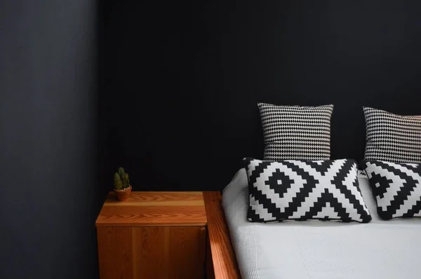 Hermoso plano interior de una cama con un pequeño estante de madera en el lado y paredes de color azul oscuro — Foto de Stock