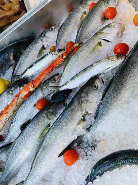 Tiro vertical de peixes e pernas de caranguejo com tomates e limão em um gelo — Fotografia de Stock