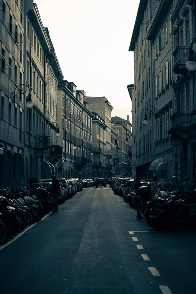 Uma foto dramática de uma rua estreita em uma cidade urbana com motocicletas estacionadas e carros — Fotografia de Stock