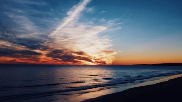 Прекрасний знімок берегової лінії і моря з захоплюючими хмарами в небі на світанку — стокове фото