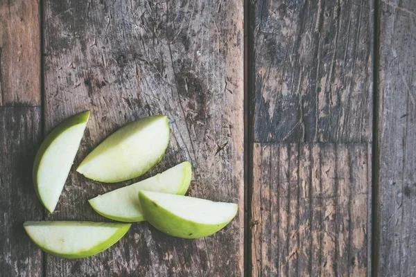 Closeup overhead shot of a sliced green apple on a wooden background