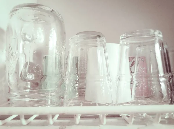 Closeup tiro de copos e um jarro em um rack de louça — Fotografia de Stock