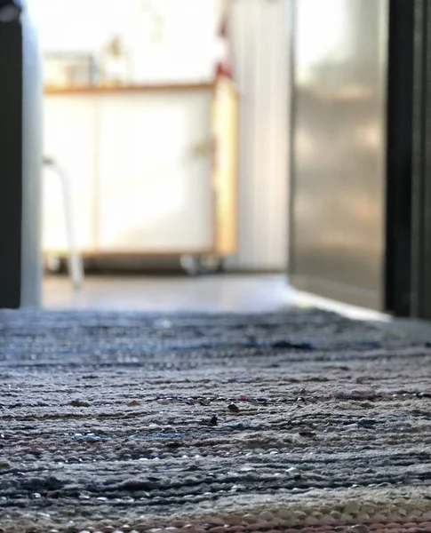 Mise au point sélective verticale gros plan d'un tapis près d'une porte de cuisine dans un arrière-plan flou — Photo
