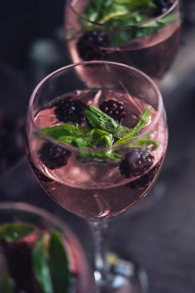 Primer plano selectivo vertical de una copa de vino llena de líquido con moras y hojas —  Fotos de Stock