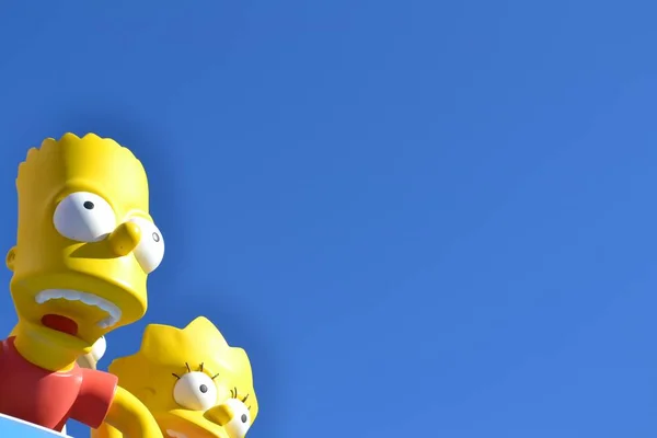 Slight closeup shot of Bart and Lisa Simpsons statues under a blue sky — Stock Photo, Image