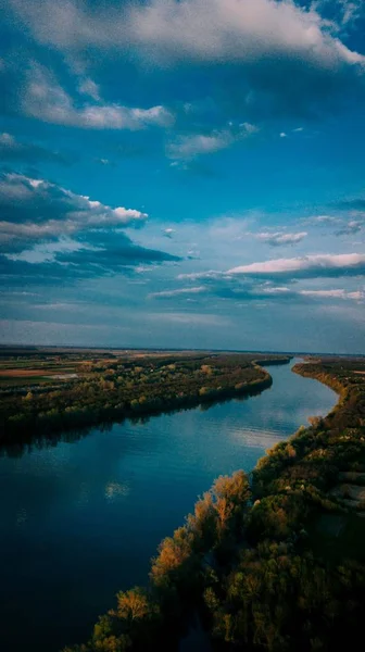 Κάθετη βολή ενός όμορφου ποταμού σε ένα χωράφι με μαγευτικά σύννεφα στον ουρανό — Φωτογραφία Αρχείου