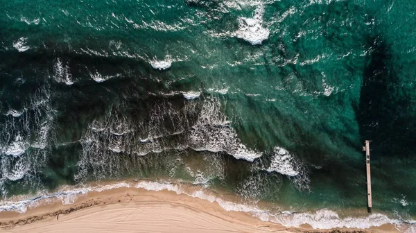 Aerial shot of green ocean waves with a sandy seashore — Stock Photo, Image
