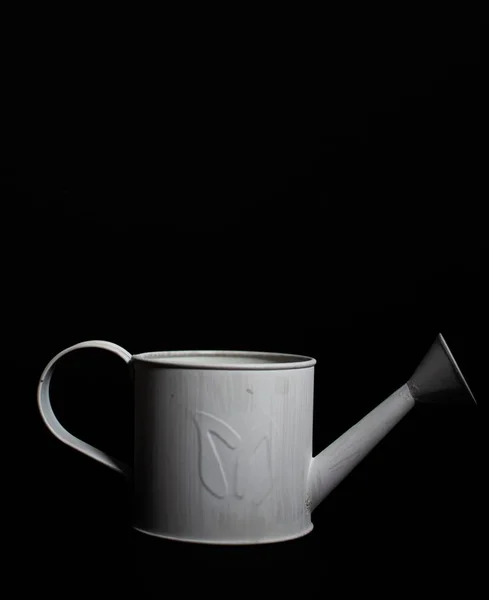 Vertikale Einzelaufnahme einer weißen Gießkanne auf schwarzem Hintergrund — Stockfoto