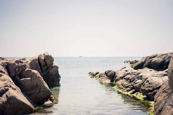 Ampio colpo di formazioni rocciose sul corpo d'acqua sotto un cielo limpido — Foto Stock