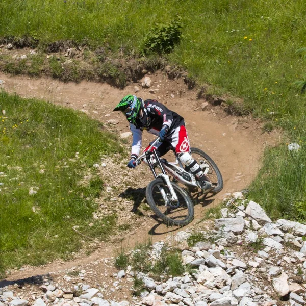 Tiro vertical de um motociclista usando uma roupa de ciclismo e capacete montando uma bicicleta na montanha — Fotografia de Stock