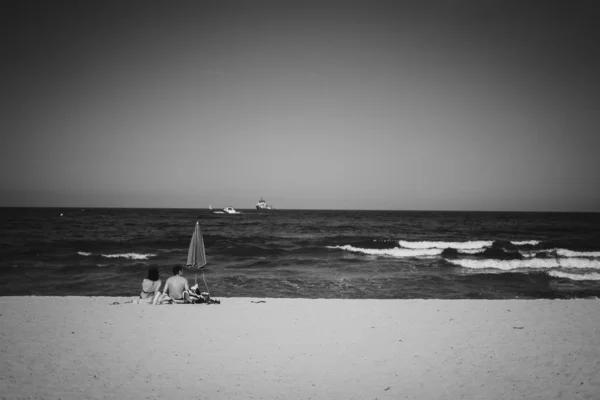 Grayscale Shot Female Male Sitting Sandy Seashore Sea — Stock Photo, Image