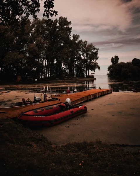 Potret vertikal dari perahu karet merah dan hitam yang merapat di dekat dermaga kayu — Stok Foto