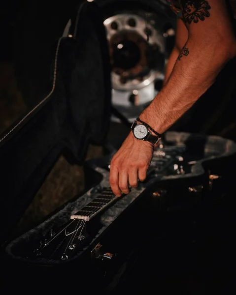 Vertikalt skott av en musiker händer att få sin elgitarr ur fallet — Stockfoto