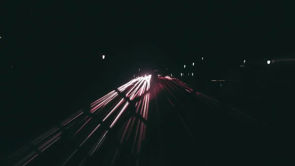 Timelapse shot of a road through a chain link fence during night — Stock Photo, Image