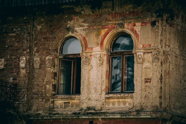 Altes verwittertes Steingebäude mit hölzernen gruseligen Fenstern im Grünen — Stockfoto