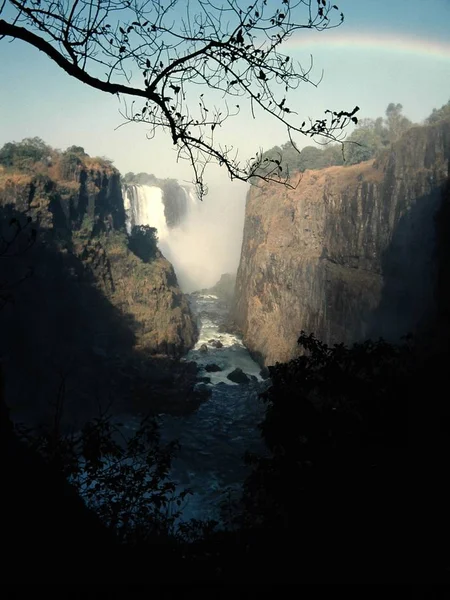 崖の真ん中の水流の垂直方向のショットと距離の滝 — ストック写真