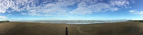 Vue panoramique d'un rivage sous un ciel nuageux bleu pendant la journée — Photo