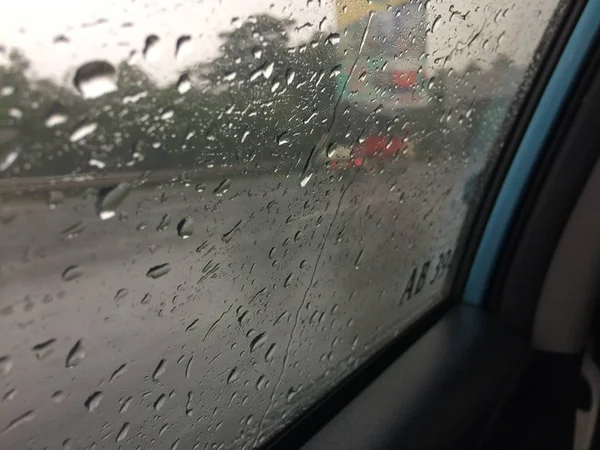 Bulanık arka planlı bir araba penceresinde yağmur damlalarının yakın çekimi — Stok fotoğraf