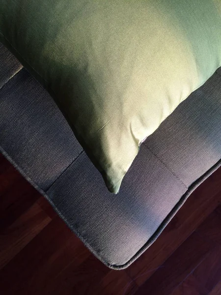 Tiro vertical de una almohada en un sofá con un suelo de madera en el fondo —  Fotos de Stock