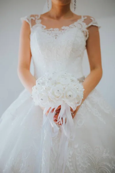 Vertikale Aufnahme der Braut in einem schönen weißen Brautkleid auf grauem Hintergrund — Stockfoto